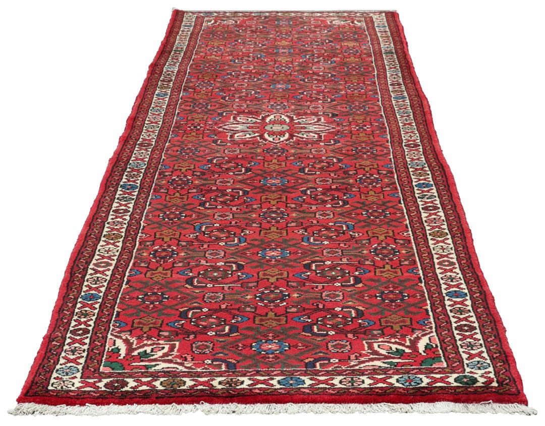A hand-knotted runner rug from the Middle East featuring a deep red field and geometric motifs