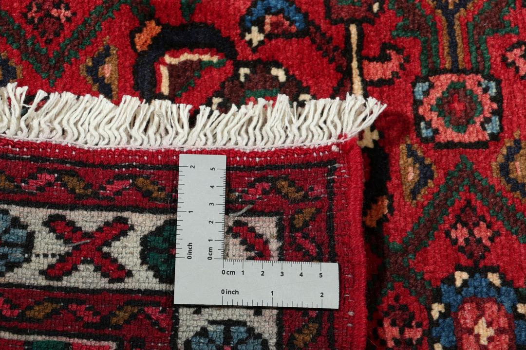 A hand-knotted runner rug from the Middle East featuring a deep red field and geometric motifs
