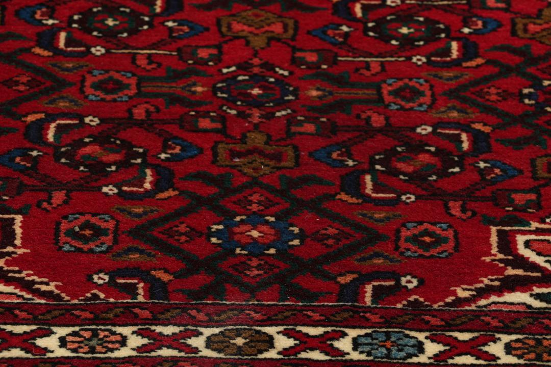 A hand-knotted runner rug from the Middle East featuring a deep red field and geometric motifs
