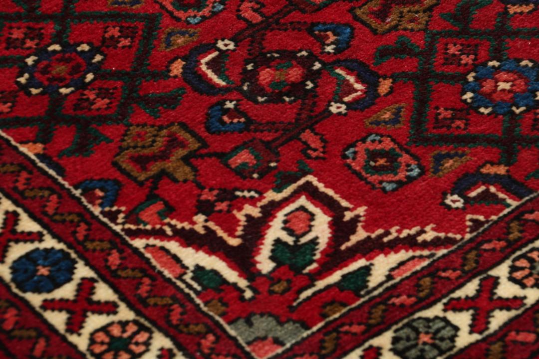 A hand-knotted runner rug from the Middle East featuring a deep red field and geometric motifs