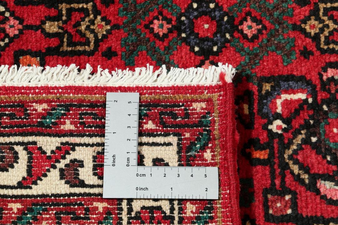 Een handgeknoopte Hosseinabad loper met een dieprood veld en geometrische medaillons.