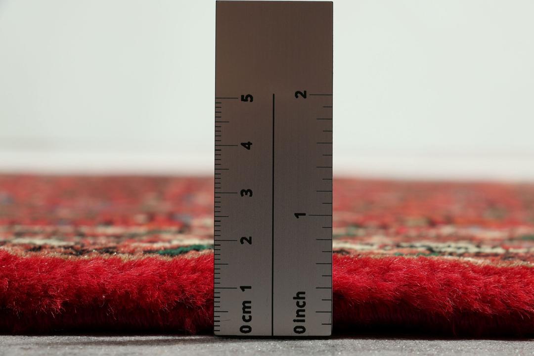 Een handgeknoopte Hosseinabad loper met een dieprood veld en geometrische medaillons.