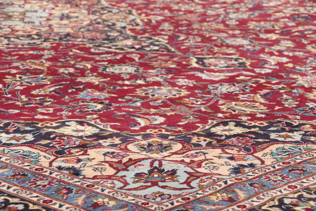 A hand-knotted Mashad rug from the Middle East with a deep red field and intricate floral medallion.