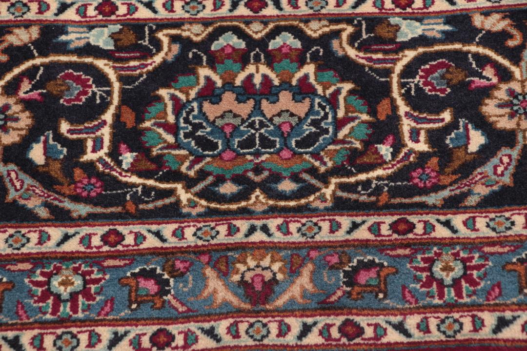A hand-knotted Mashad rug from the Middle East with a deep red field and intricate floral medallion.