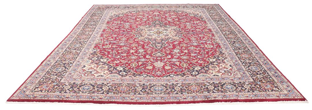 A hand-knotted Mashad rug from the Middle East with a deep red field and intricate floral medallion.