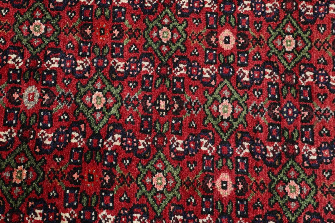 A long, hand-knotted Hosseinabad runner with a red field and traditional geometric motifs.