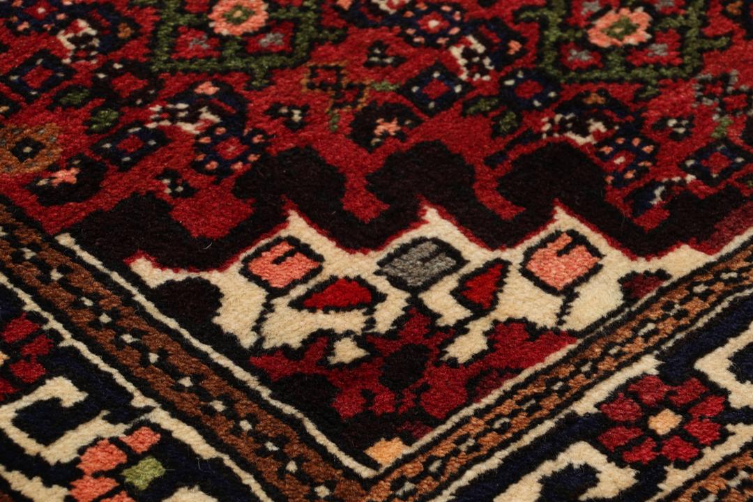 A long, hand-knotted Hosseinabad runner with a red field and traditional geometric motifs.