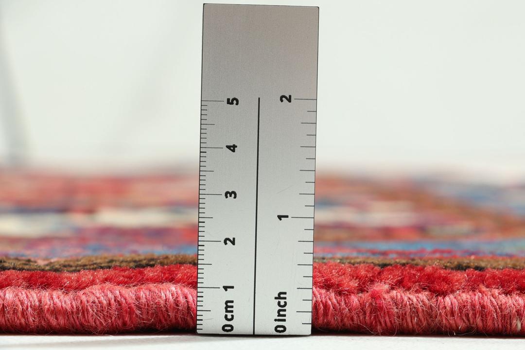 Een handgeknoopt Hamadan-tapijt uit het Midden-Oosten met een rood en blauw medaillonontwerp.