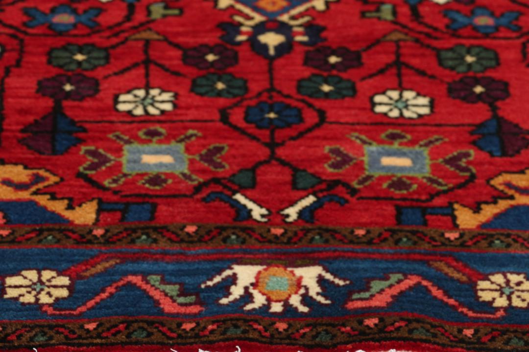 Een handgeknoopt Hamadan-tapijt uit het Midden-Oosten met een rood en blauw medaillonontwerp.