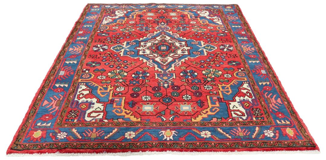 Een handgeknoopt Hamadan-tapijt uit het Midden-Oosten met een rood en blauw medaillonontwerp.