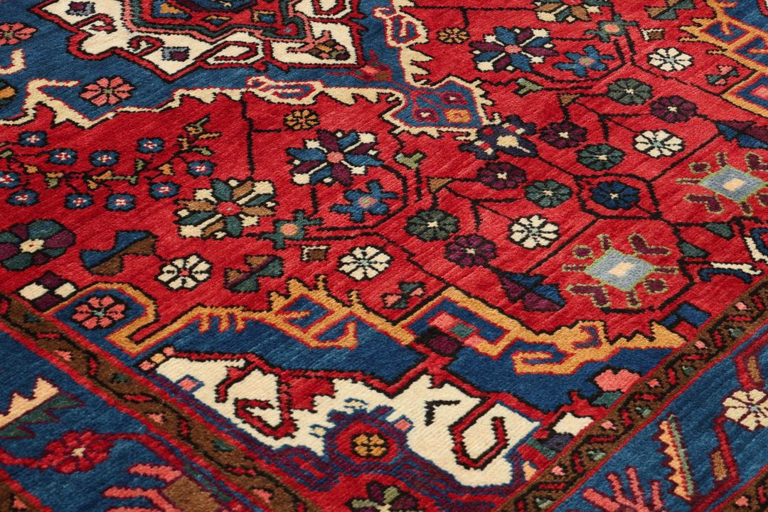 Een handgeknoopt Hamadan-tapijt uit het Midden-Oosten met een rood en blauw medaillonontwerp.