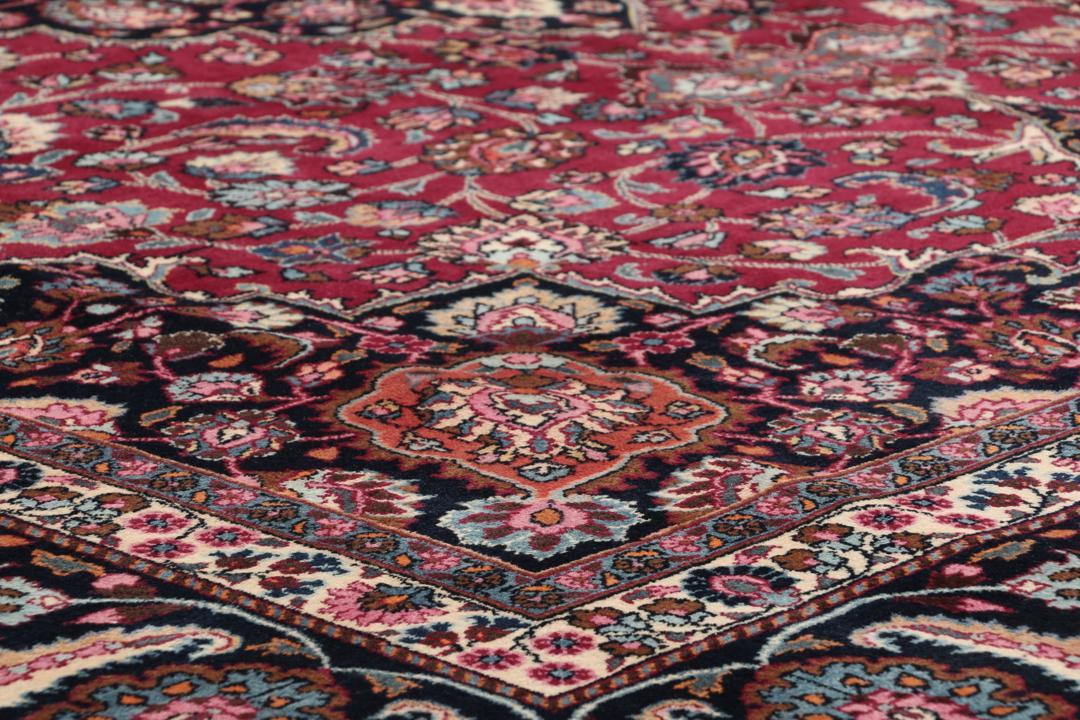Hand-knotted Mashad rug from the Middle East featuring a dark-red field and floral patterns
