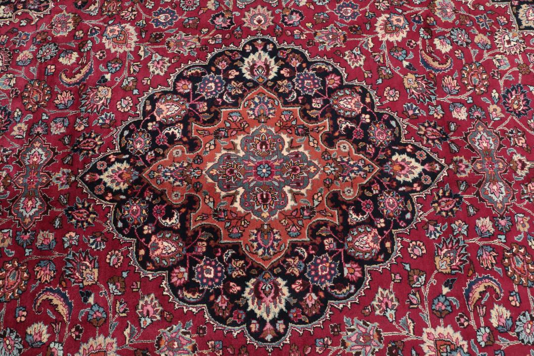 Hand-knotted Mashad rug from the Middle East featuring a dark-red field and floral patterns