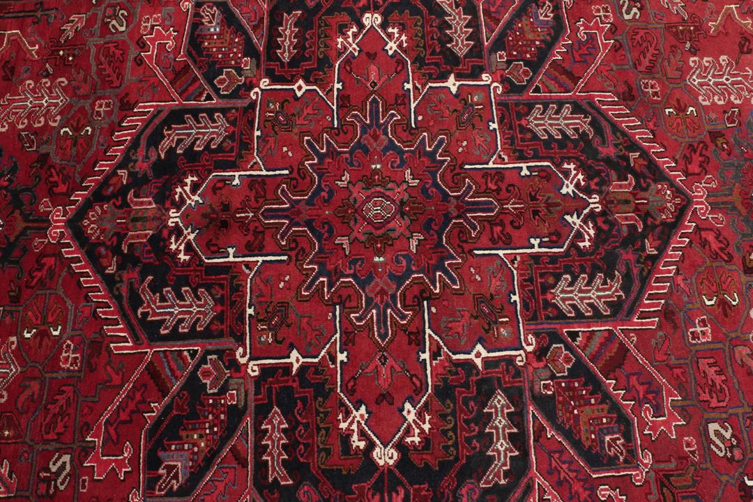A hand-knotted Heriz rug from the Middle East in deep red and dark tones.