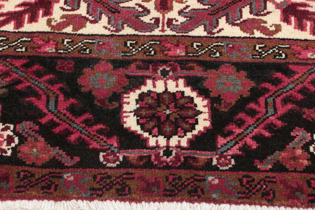 A hand-knotted Heriz rug from the Middle East in deep red and dark tones.