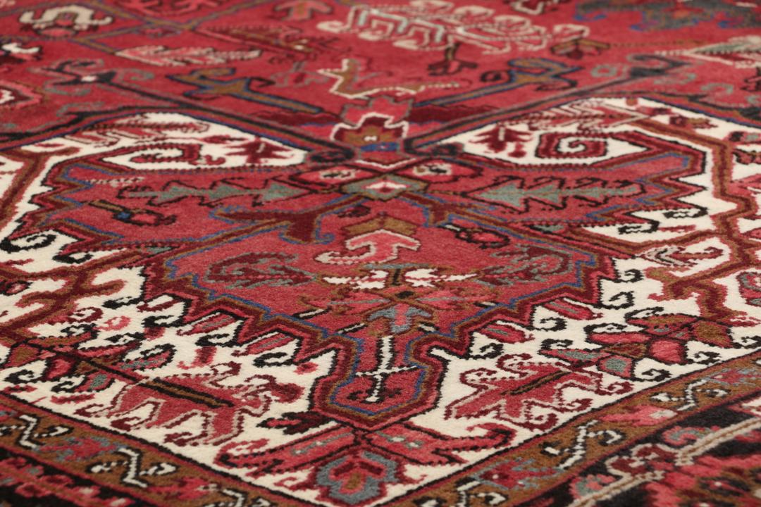 A hand-knotted Heriz rug from the Middle East in deep red and dark tones.