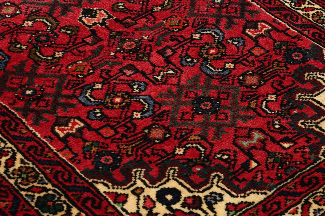 Hand-knotted Hosseinabad runner rug with a vibrant red field, originating from the Middle East.