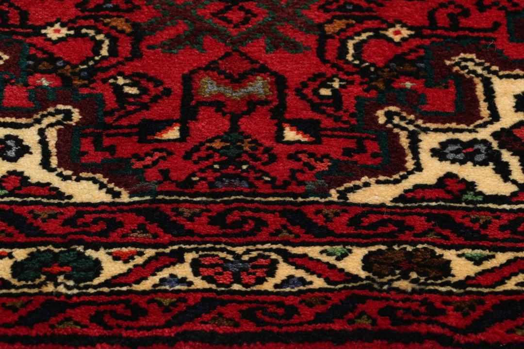 Hand-knotted Hosseinabad runner rug with a vibrant red field, originating from the Middle East.