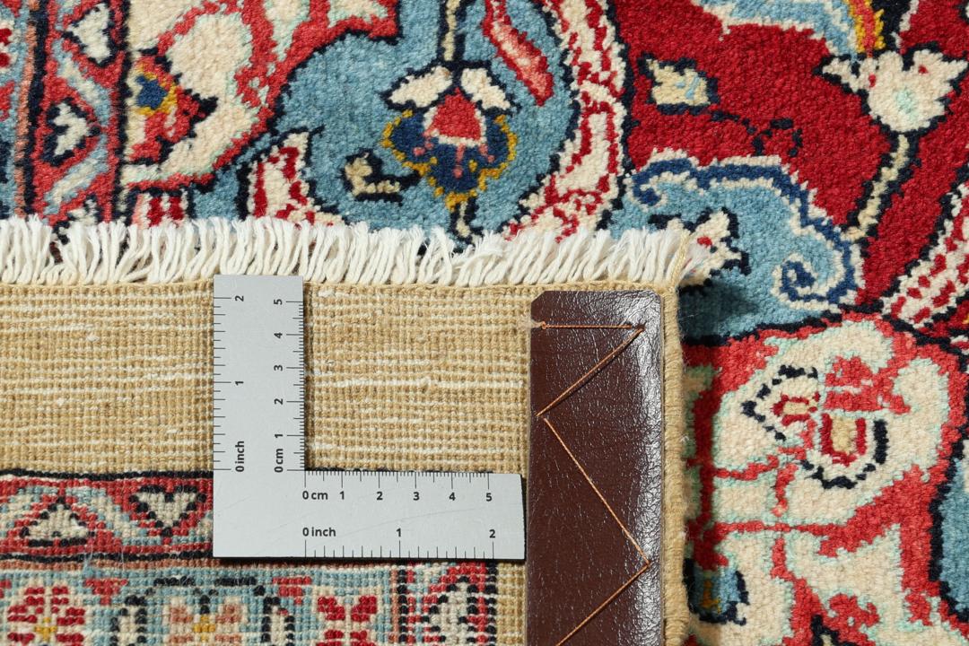 A hand-knotted Sarough rug from the Middle East with a beige field and red accents.