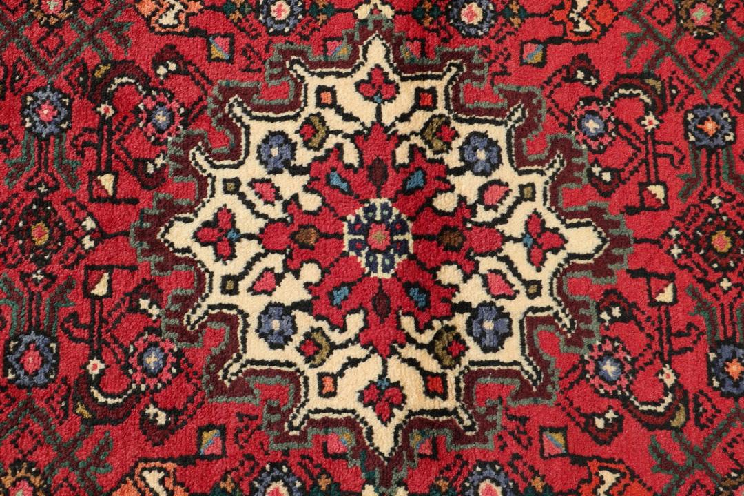 Hand-knotted Hosseinabad runner rug with a vibrant red field, originating from the Middle East.