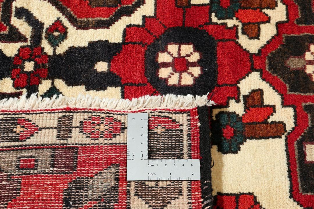 A hand-knotted Middle Eastern Bakhtiari rug featuring a bold red and black floral medallion design.