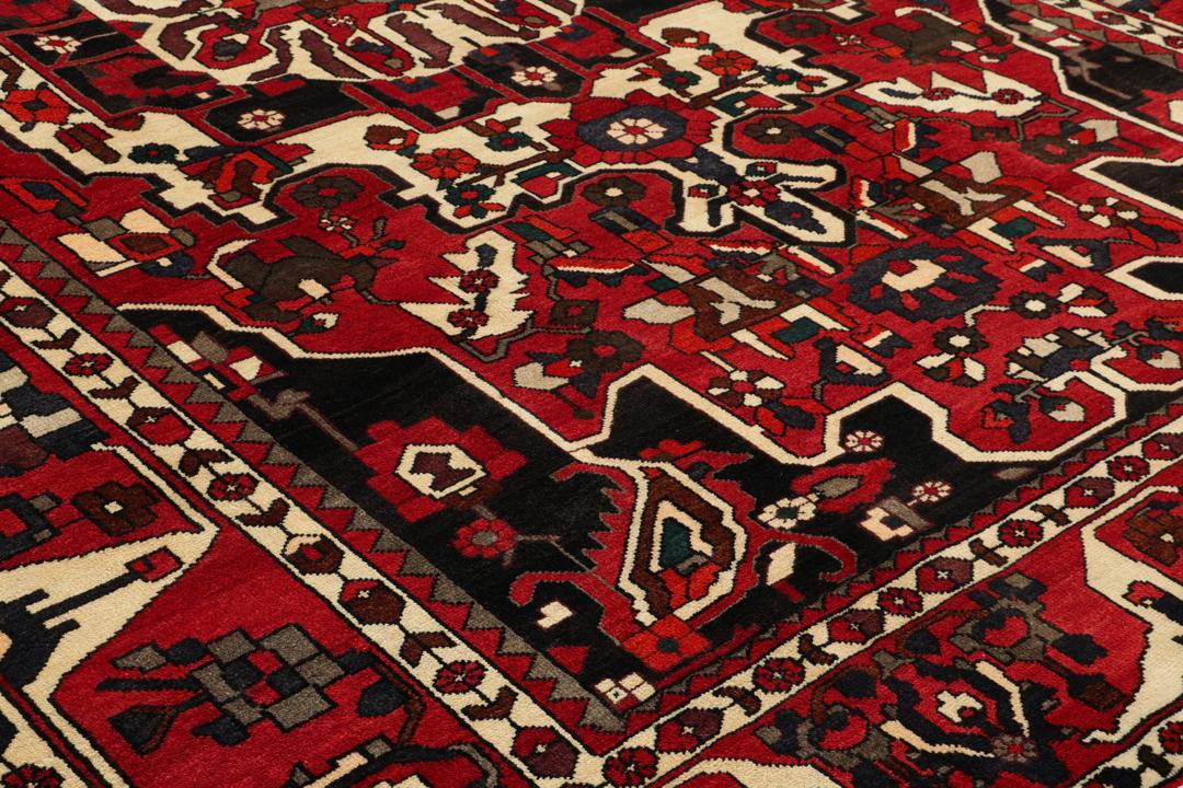 A hand-knotted Middle Eastern Bakhtiari rug featuring a bold red and black floral medallion design.
