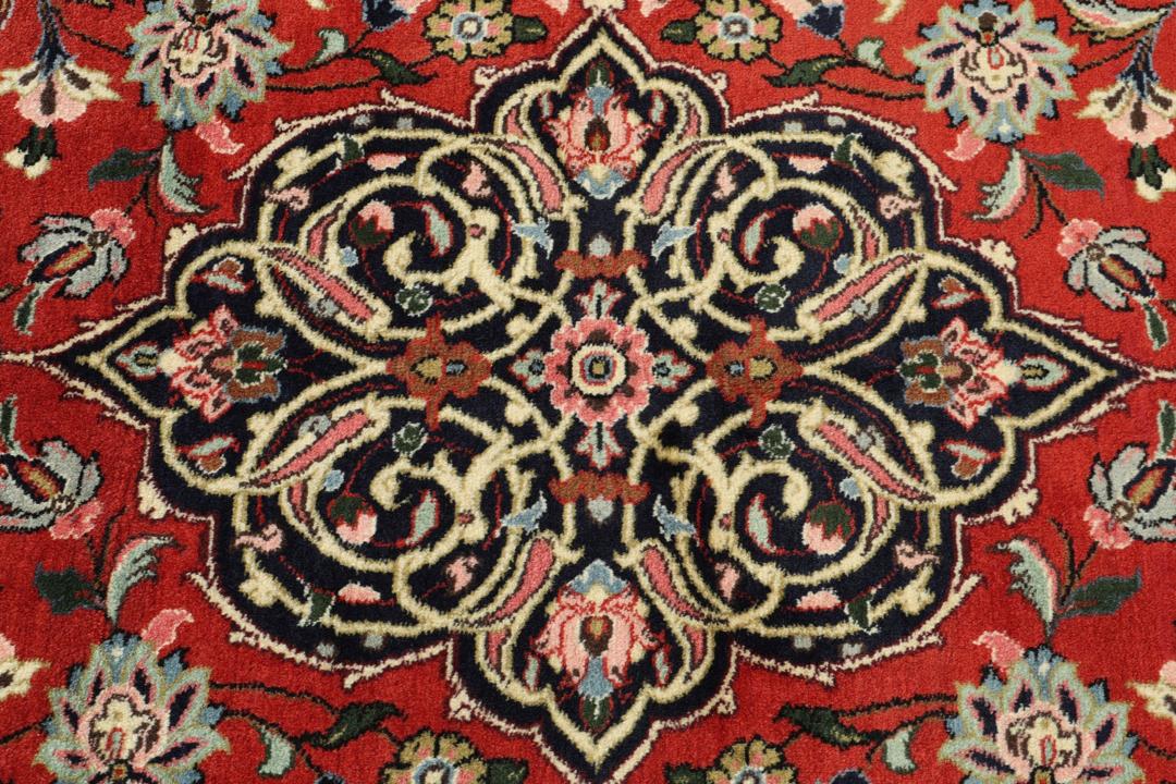 Hand-knotted Sarough rug from the Middle East with a red field and floral patterns.