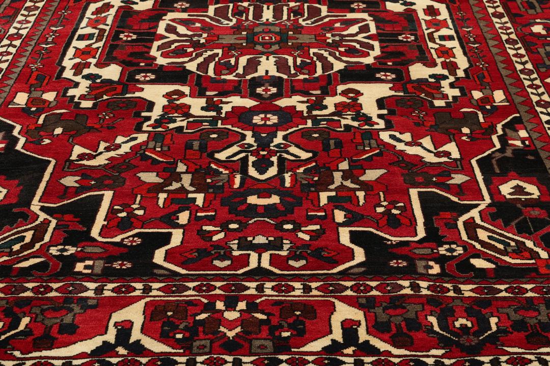 A hand-knotted Middle Eastern Bakhtiari rug featuring a bold red and black floral medallion design.