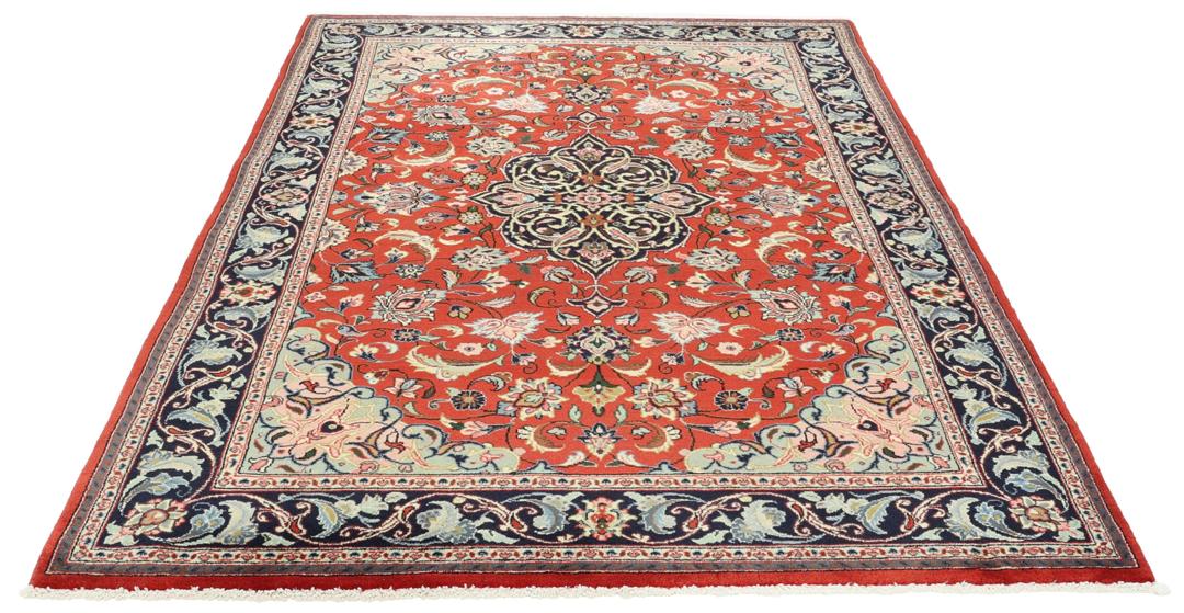 Hand-knotted Sarough rug from the Middle East with a red field and floral patterns.