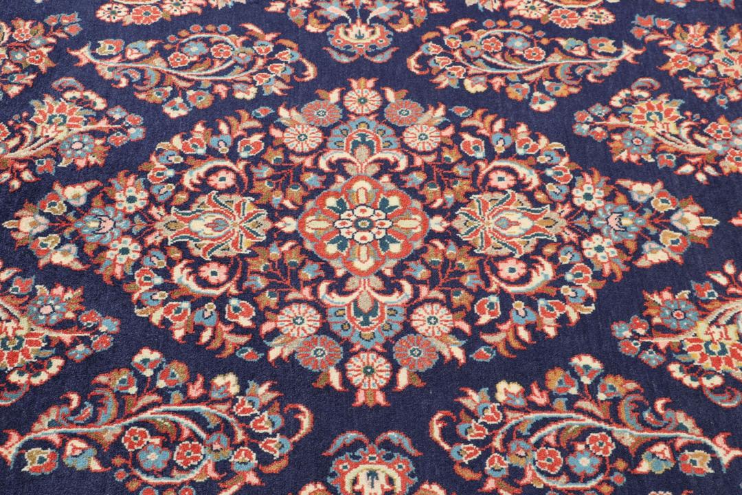 Een handgeknoopt Mahal-tapijt uit het Midden-Oosten met een donkerblauw veld en rode randen.