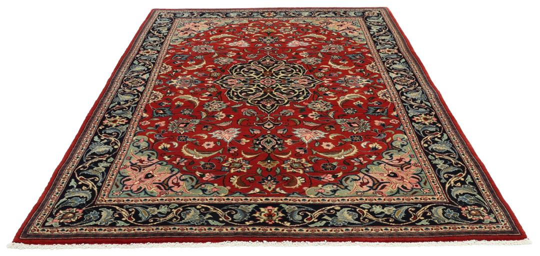 Hand-knotted Sarough rug from the Middle East with a red field and floral patterns.
