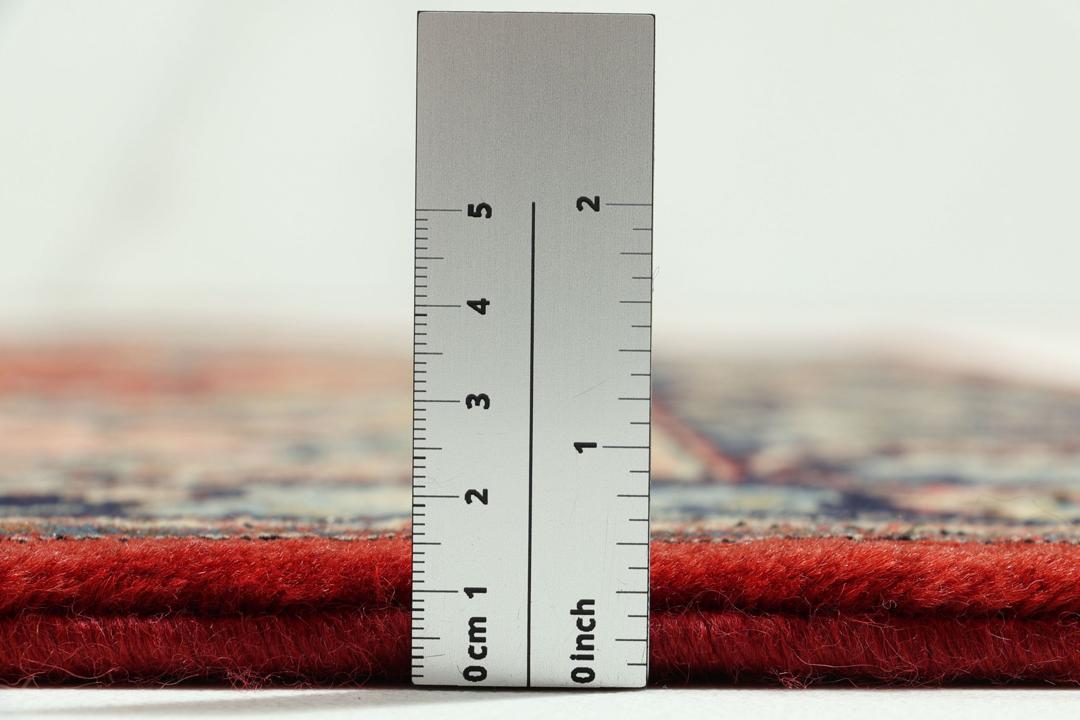Hand-knotted Sarough rug from the Middle East with a red field and floral patterns.