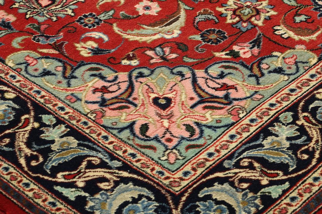 Hand-knotted Sarough rug from the Middle East with a red field and floral patterns.
