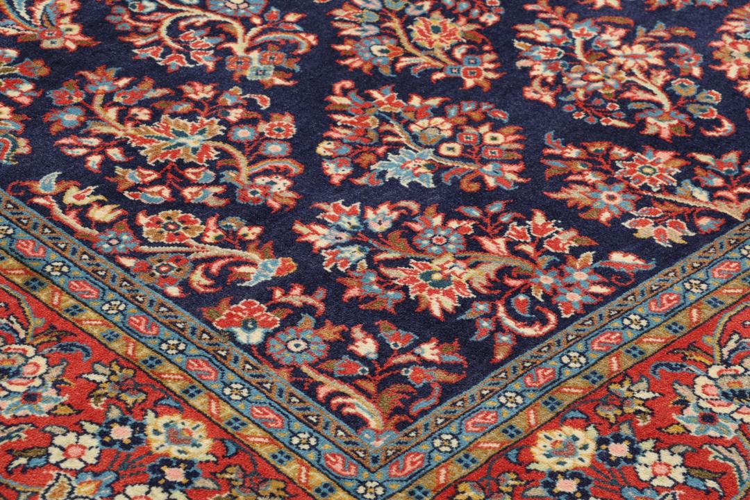 Een handgeknoopt Mahal-tapijt uit het Midden-Oosten met een donkerblauw veld en rode randen.