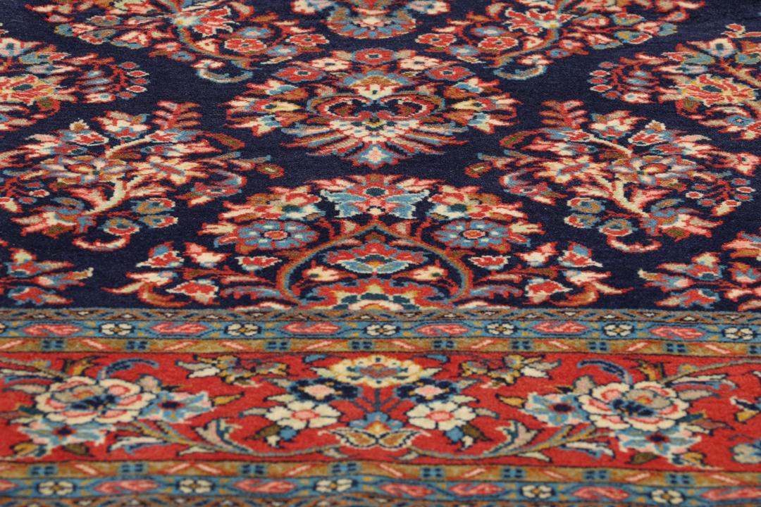 Een handgeknoopt Mahal-tapijt uit het Midden-Oosten met een donkerblauw veld en rode randen.