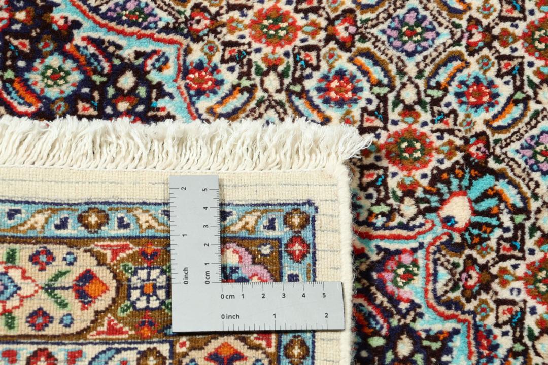 A large rectangular Moud rug from the Middle East featuring a central medallion and ornate floral patterns in multicolor wool.