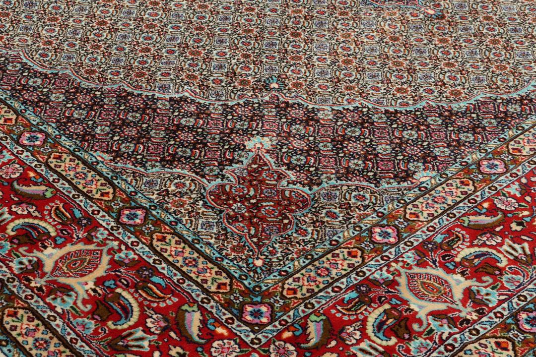 A large rectangular Moud rug from the Middle East featuring a central medallion and ornate floral patterns in multicolor wool.