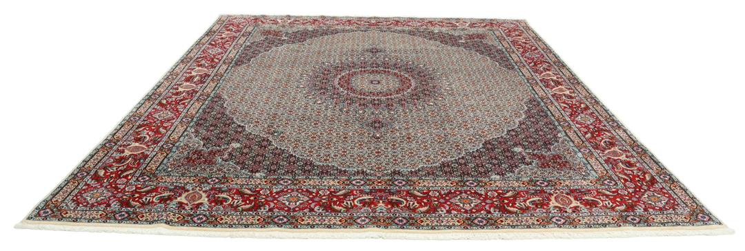 A large rectangular Moud rug from the Middle East featuring a central medallion and ornate floral patterns in multicolor wool.