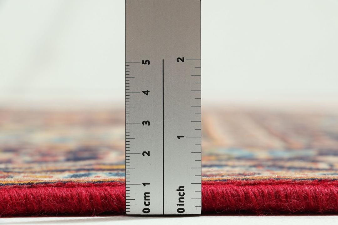 Een handgeknoopt Kashan-tapijt uit het Midden-Oosten met een rood veld en een blauw medaillon.