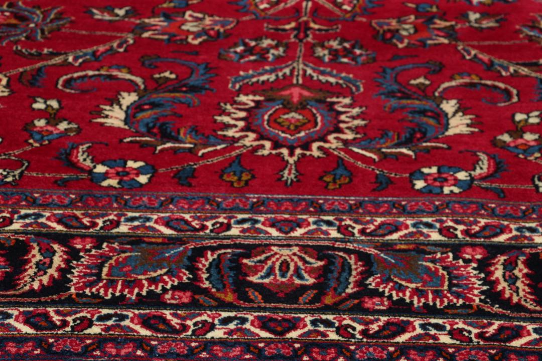 Hand-knotted Mashad rug from the Middle East in red with floral patterns.