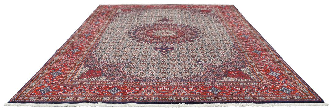 Een handgeknoopt Moud-tapijt uit het Midden-Oosten met een rood en blauw medaillonpatroon.