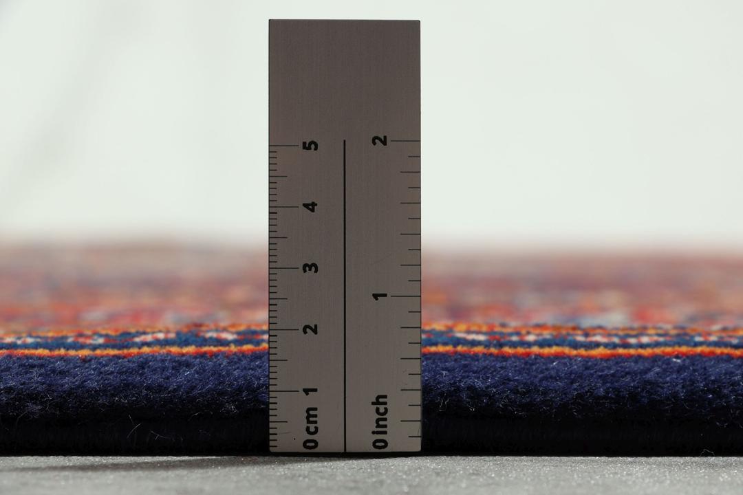 Een handgeknoopt Moud-tapijt uit het Midden-Oosten met een rood en blauw medaillonpatroon.