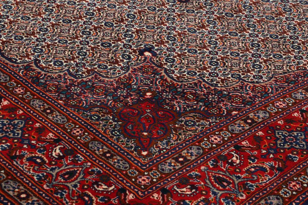 Een handgeknoopt Moud-tapijt uit het Midden-Oosten met een rood en blauw medaillonpatroon.