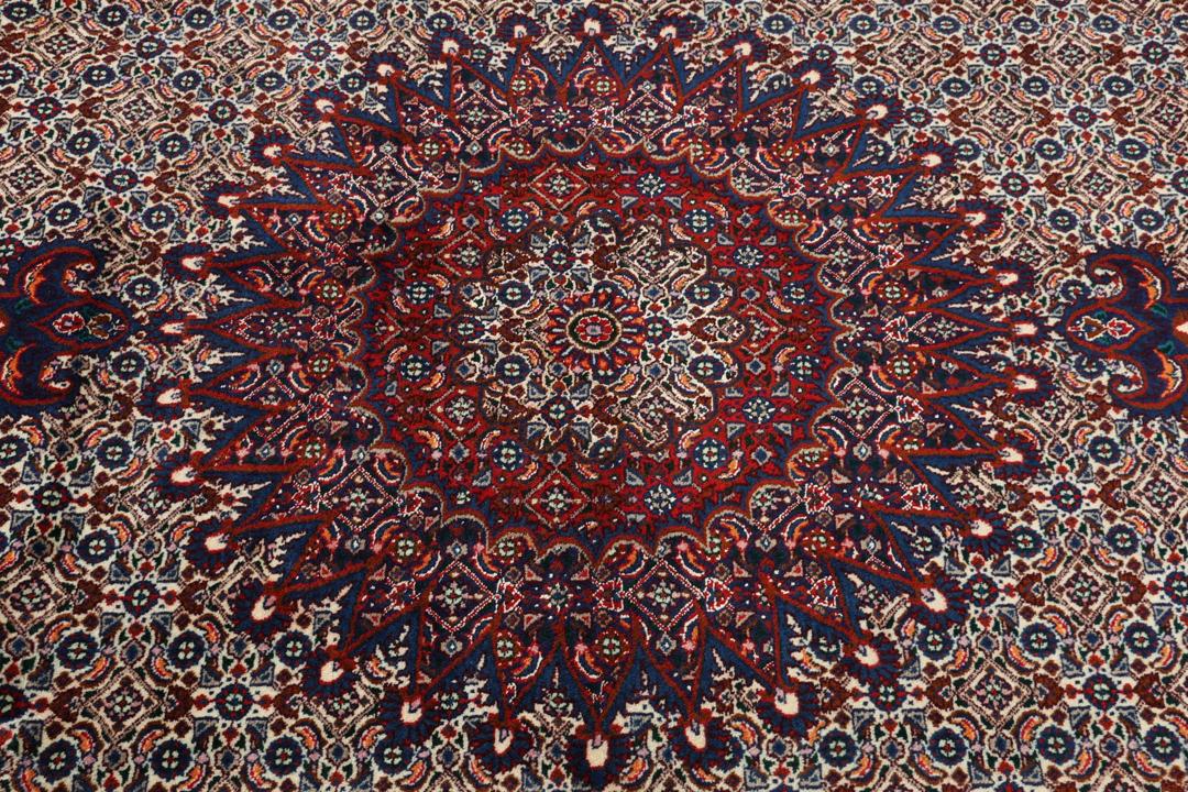 Een handgeknoopt Moud-tapijt uit het Midden-Oosten met een rood en blauw medaillonpatroon.