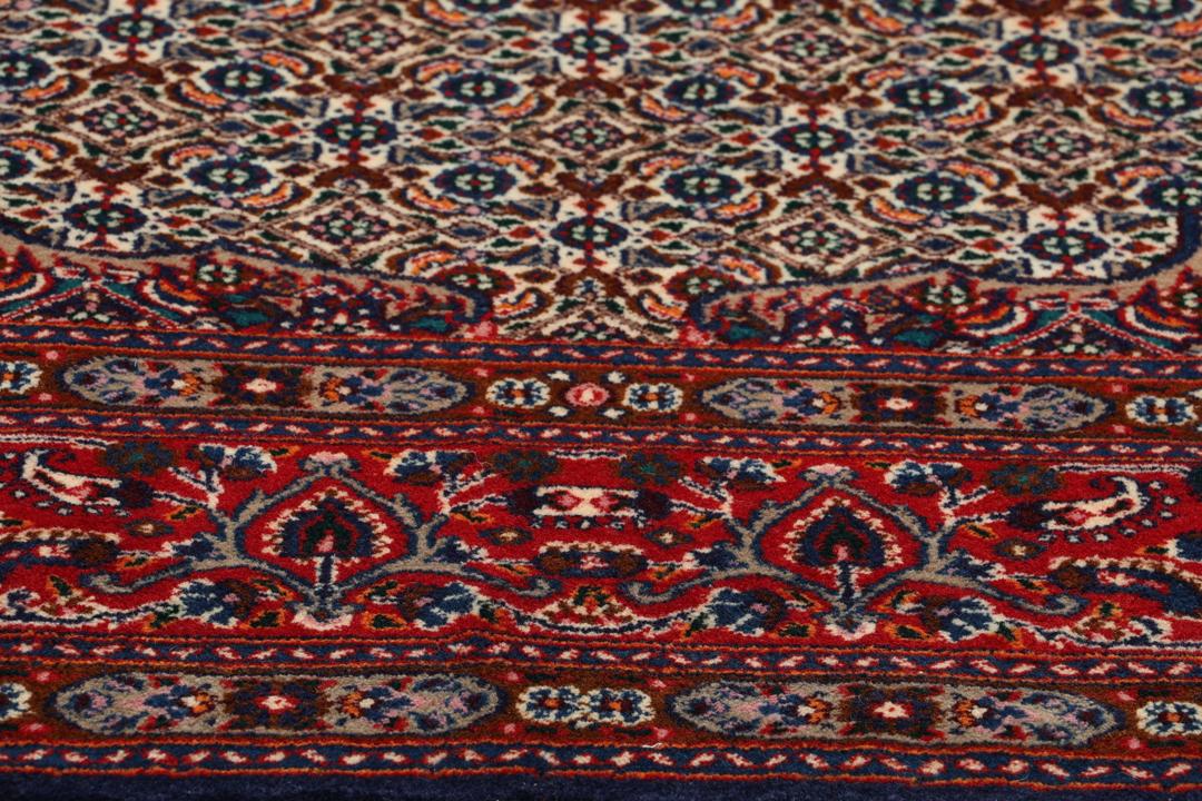 Een handgeknoopt Moud-tapijt uit het Midden-Oosten met een rood en blauw medaillonpatroon.