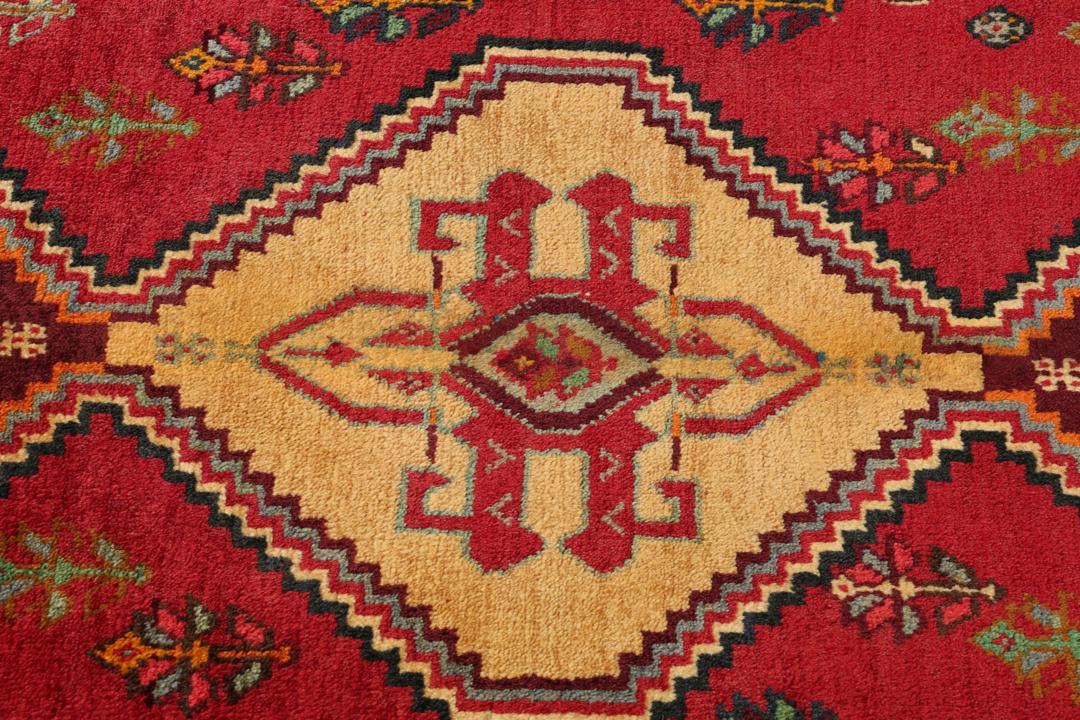 Handgeknoopt tapijt uit het Midden-Oosten met een rood veld en geometrische medaillons
