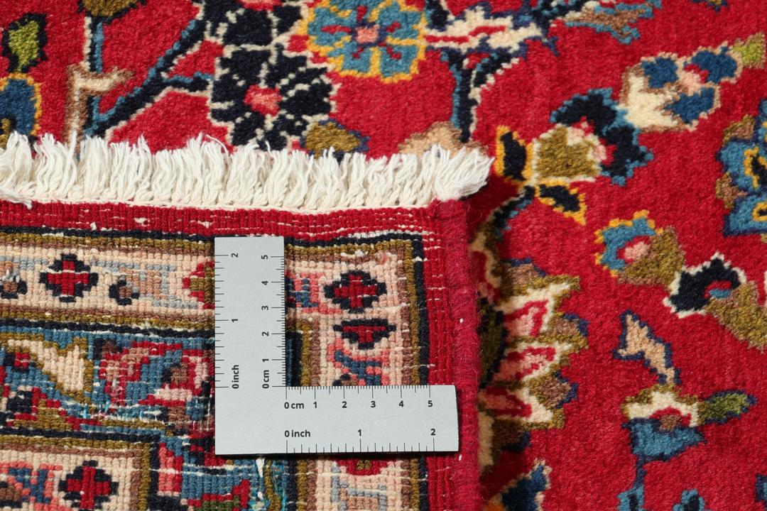A hand-knotted Mashad rug from the Middle East in deep red and blue tones.