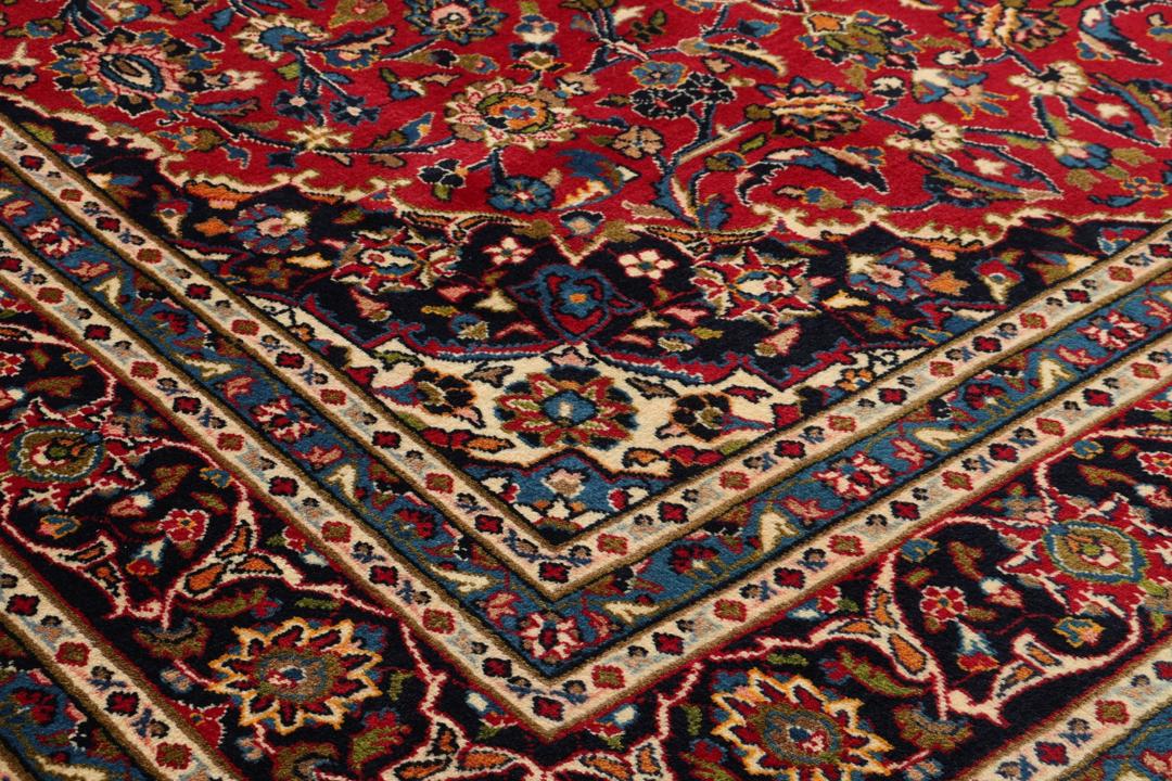 A hand-knotted Mashad rug from the Middle East in deep red and blue tones.