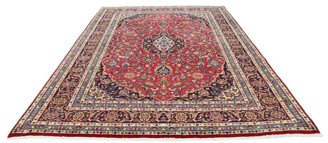 A hand-knotted Mashad rug from the Middle East in deep red and blue tones.