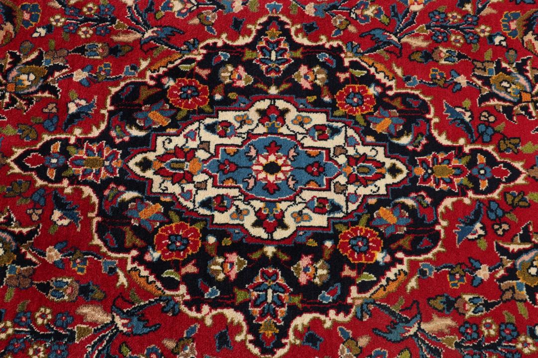 A hand-knotted Mashad rug from the Middle East in deep red and blue tones.